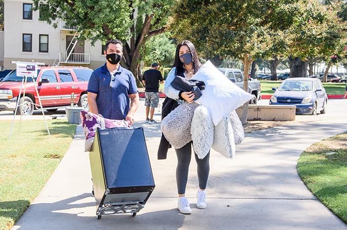 A student moves belongings into her residence hall, with help from family members and friends.