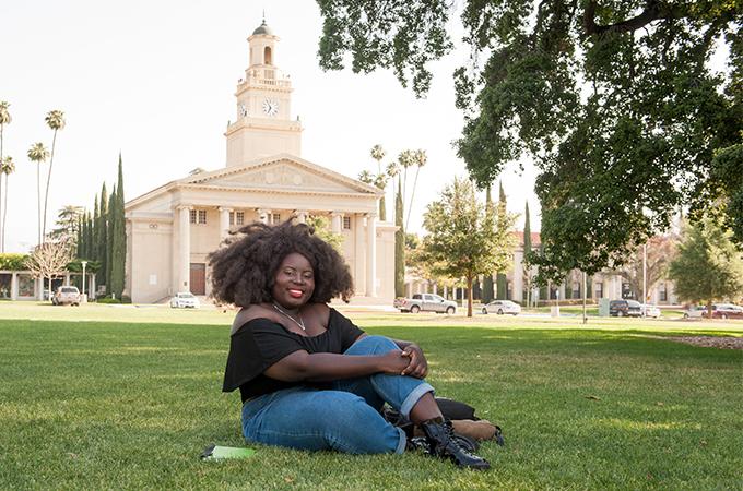 A student sits on the Quad in front of the Memorial Chapel at the University of Redlands.