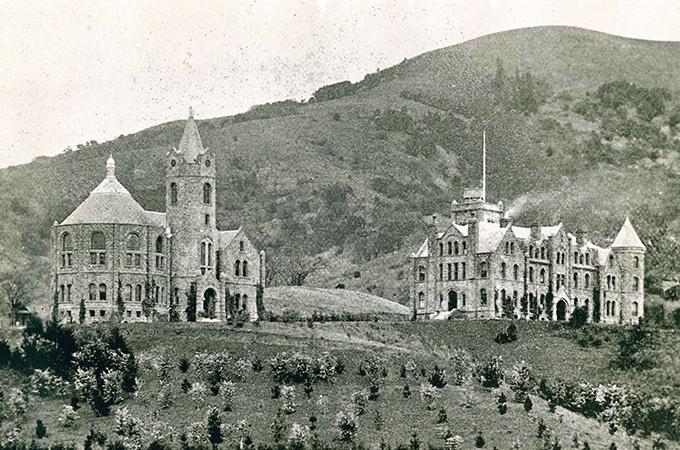 Two buildings sit on a hill in a historic black and white photograph.