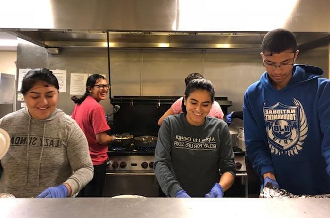 University of Redlands students prepare food in a kitchen.